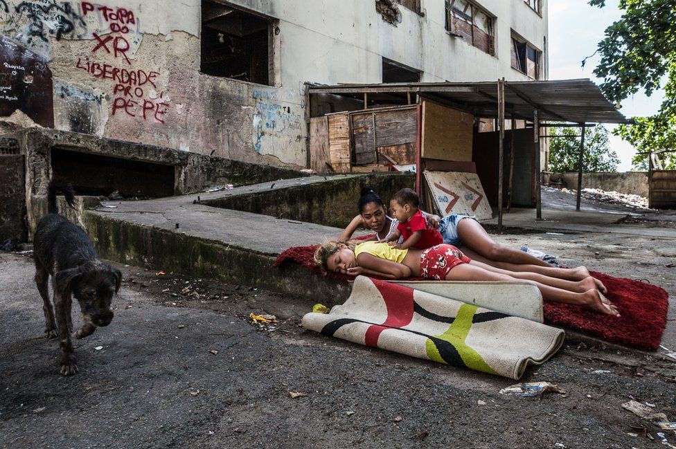 Girls playing with a baby on a carpet in front of the abandoned IBGE building, 'Favela' Mangueira community, Rio de Janeiro, Brazil