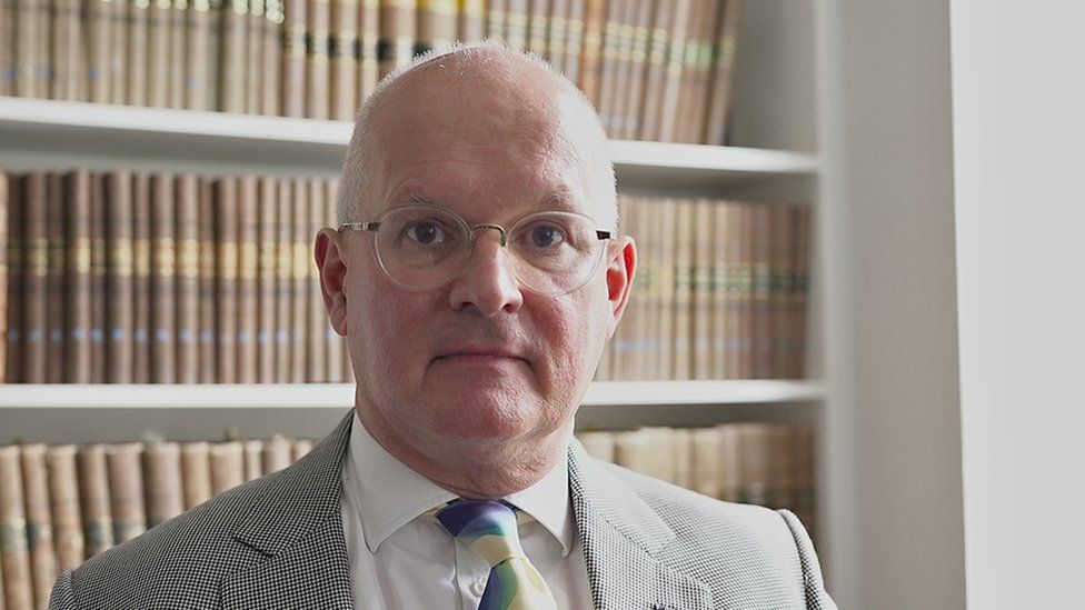 Barrister Paul Marshall, standing in front of a bookcase of legal volumes
