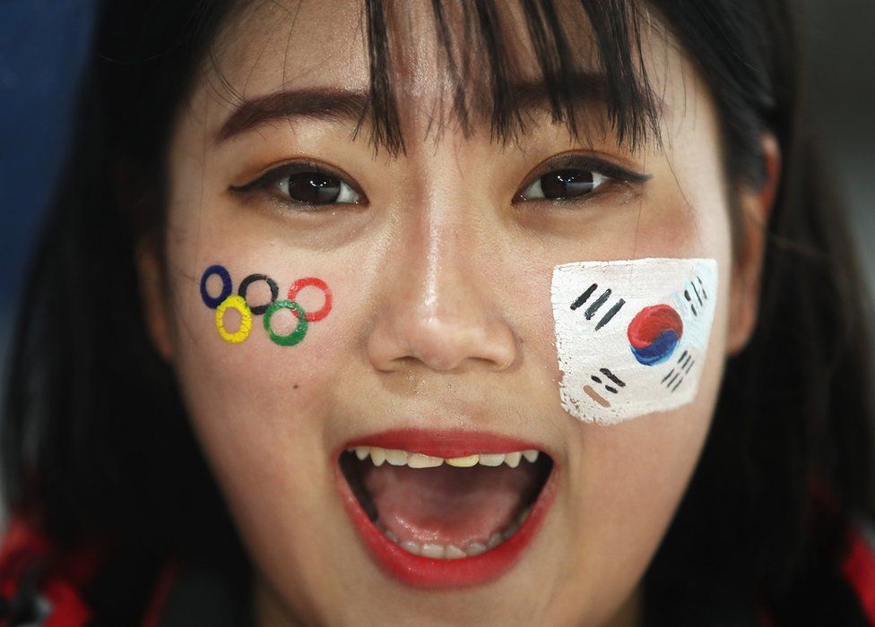 A South Korea fan smiles with logos on her face