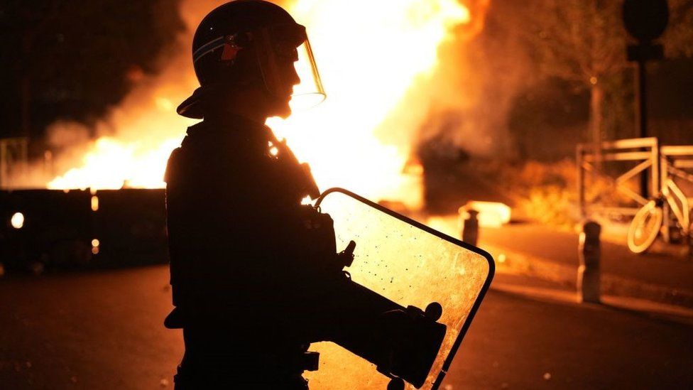 Пожарный наблюдает, как горят автомобили после беспорядков в Нантере, к западу от Парижа, 28 июня 2023 года, на следующий день после того, как полиция выстрелила в грудь 17-летнему мальчику в упор в этом западном пригороде Парижа.