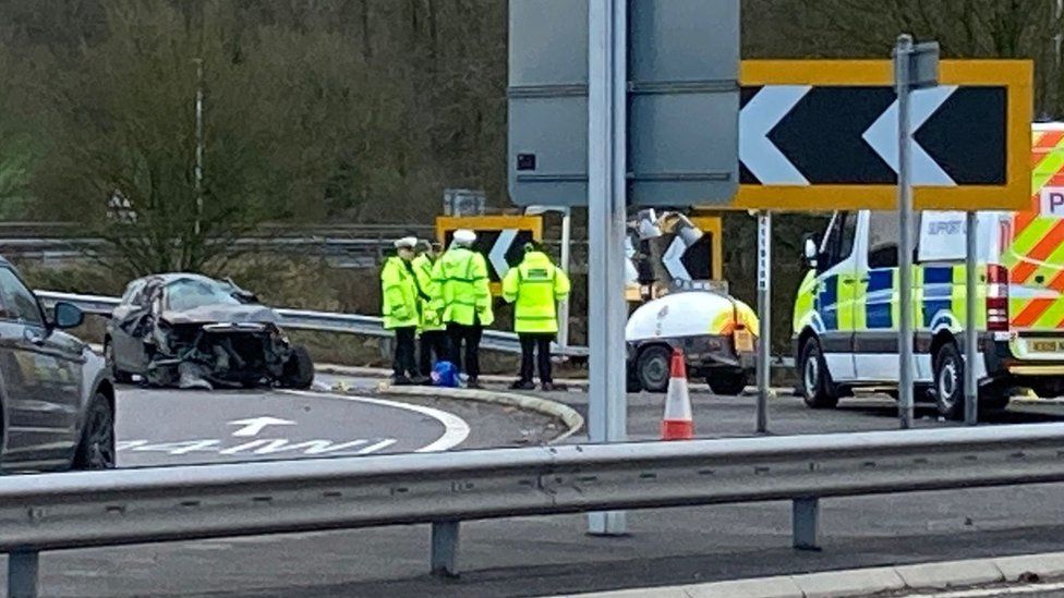 Scene of the crash showing a badly damaged black car