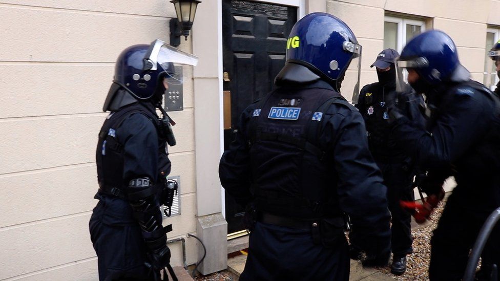 Police prepare to knock down a door