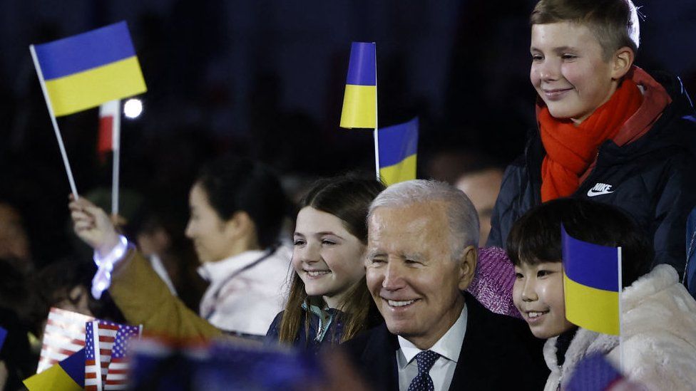 US President Joe Biden stands amid children cheering with US, Polish and Ukrainian flags after he delivered a speech in front the Royal Warsaw Castle Gardens in Warsaw, Poland on February 21, 2023