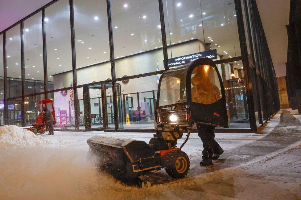 A person uses a snow blower to clear a sidewalk outside of Union Station in Chicago, Illinois, on December 22, 2022