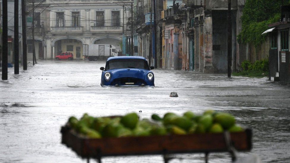 An old American car drives through a flooded street in Havana, on Augusto 29, 2023, during the passage of tropical storm Idalia.