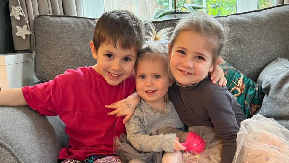 Cameron 5, Gabriella, 18 months and Isabella 3, hugging on a sofa