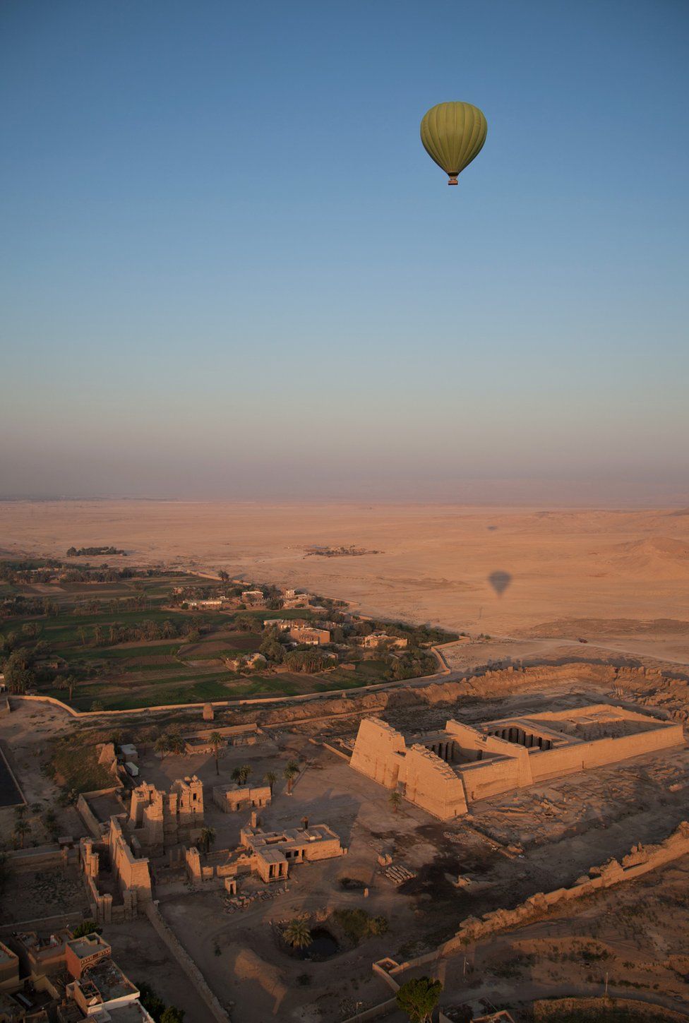 A hot air balloon flies over a temple