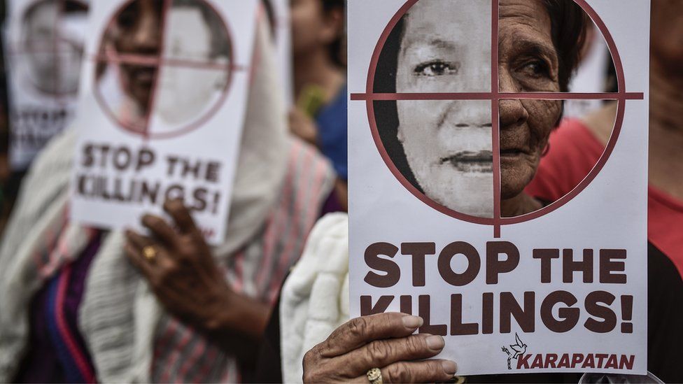 Protesters hold up pictures of victims of extrajudicial killings during Human Rights Day protests in Manila, Philippines