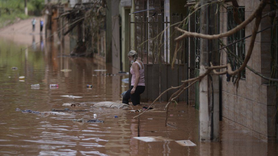 A woman wades through the water as the flood starts receding in Brazilian municipality of Raposos