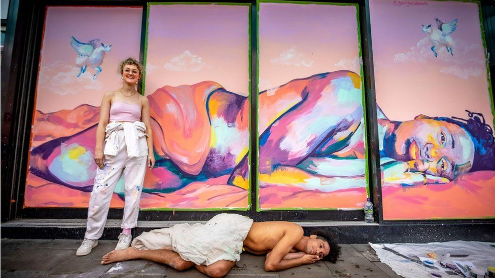 Artist in front of painting of man lying down