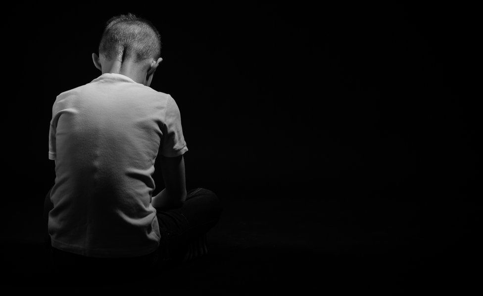 A boy sitting alone in darkness
