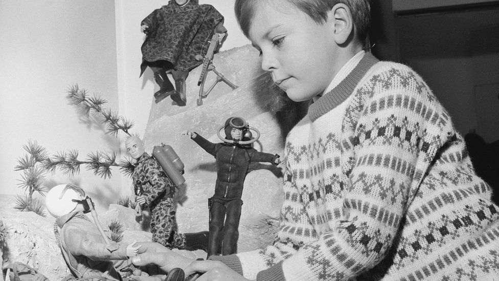 Boy playing with a display of Action Man toys