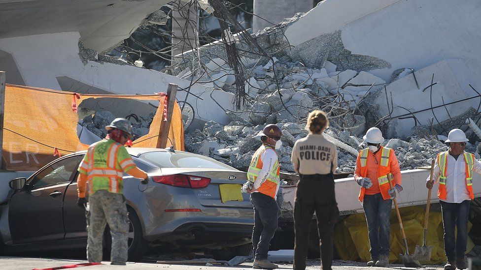 Workers, law enforcement and members of the National Transportation Safety Board investigate the scene where a pedestrian bridge collapsed in Miami, Florida.