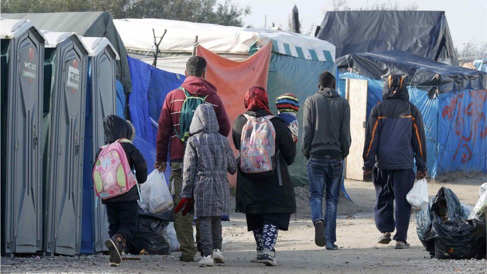 Migrants carry their belongings at the Jungle camp in Calais