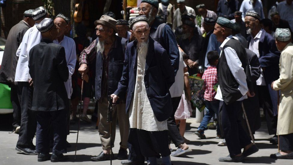 Uighur men are seen leaving a mosque after prayers in Hotan in China's Xinjiang region