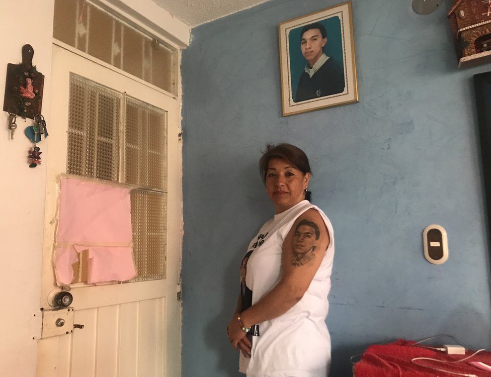 Beatriz Méndez standing in front of a photo of her son