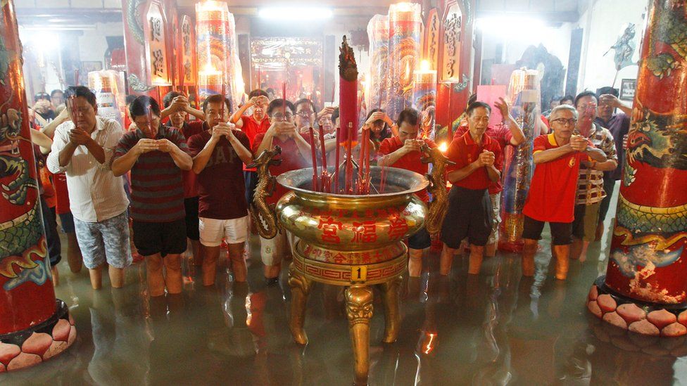 Indonesian men of Chinese descent pray at a flooded temple following a heavy rain during the Lunar New Year"s eve in Surabaya, East Java, Indonesia, Monday, Feb. 8, 2016