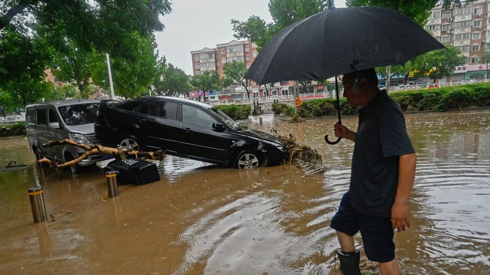 A man wades through floodwaters in Beijing