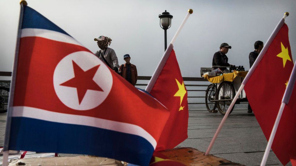 Chinese vendors sell North Korea and China flags on the boardwalk next to the Yalu river in the border city of Dandong, Liaoning province, northern China across from the city of Sinuiju, North Korea
