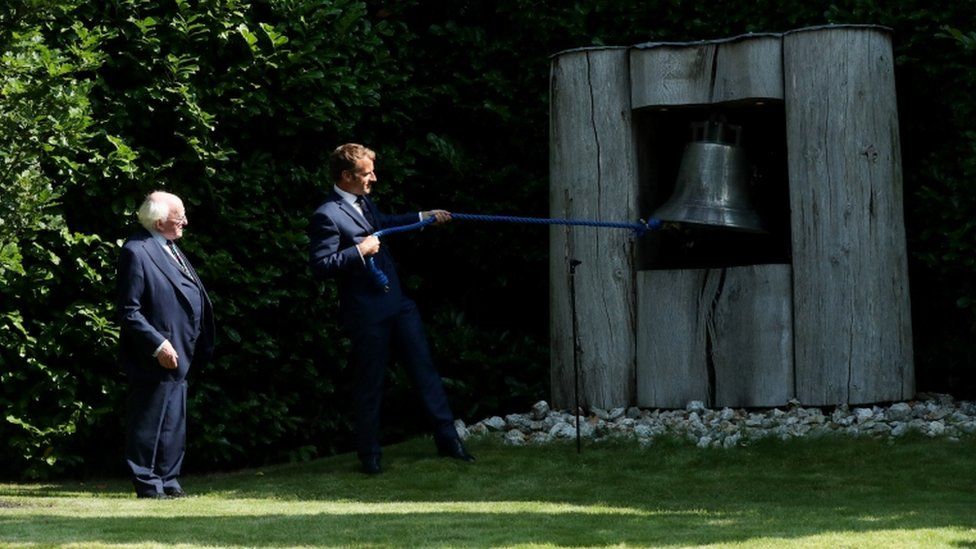 Michael D Higgins watches as Emmanuel Macron ring the peace bell at Áras an Uachtaráin