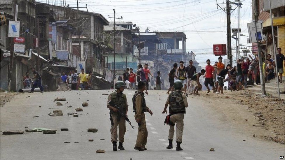 Protesters throw stone at Indian policemen during a protest in Manipur, India, Tuesday, Sept. 1, 2015.