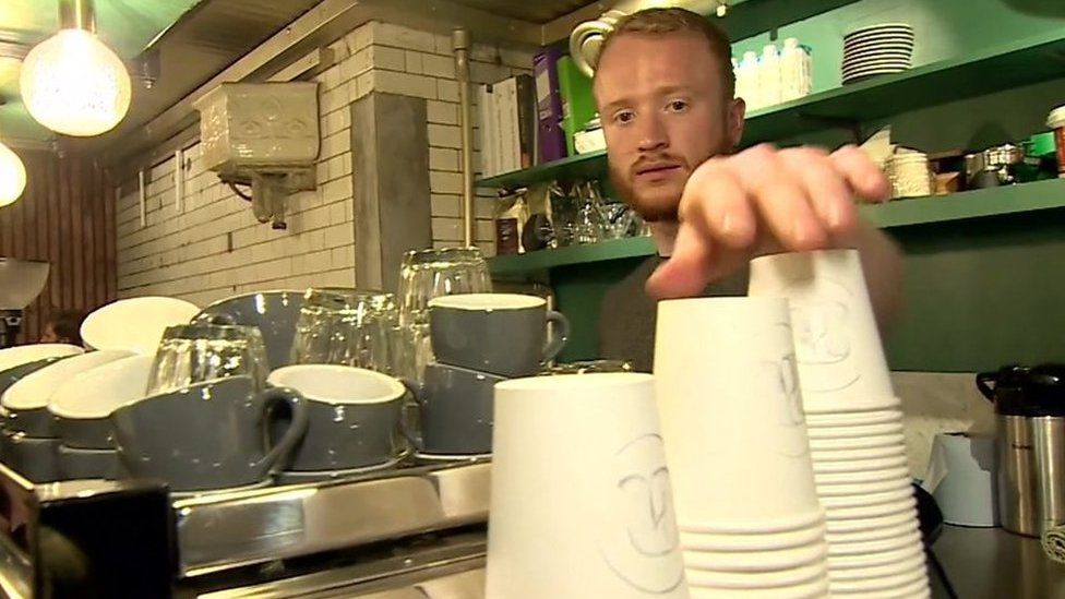 Man reaches for disposable coffee cups