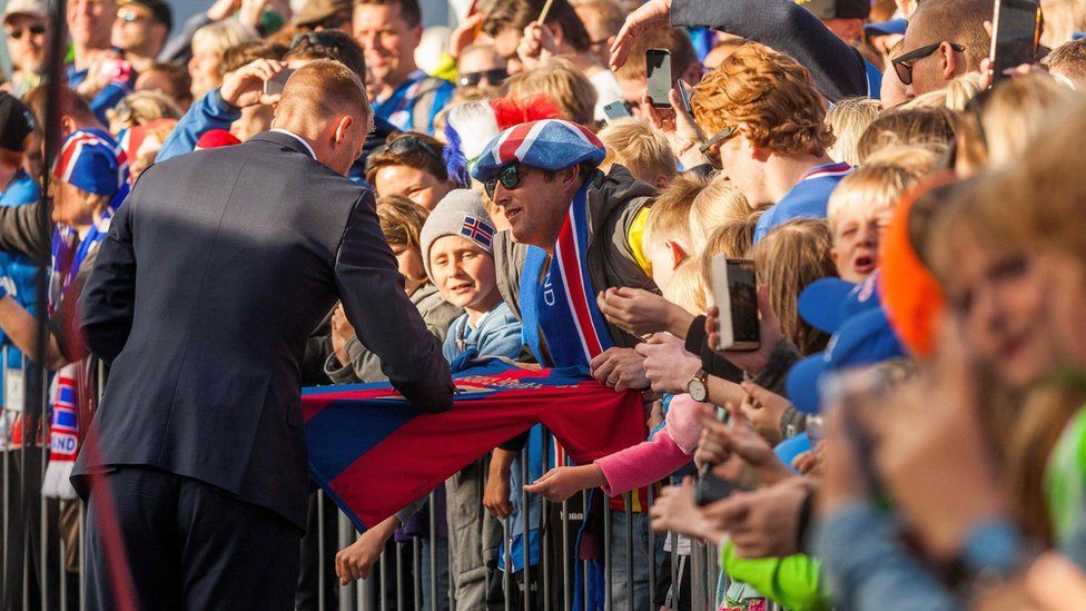 A Iceland national football player signs an autograph as he arrives with his team in Reykjavik on July 4, 2016 while people in the streets greet them as winners after they lost against France during the the Euro 2016