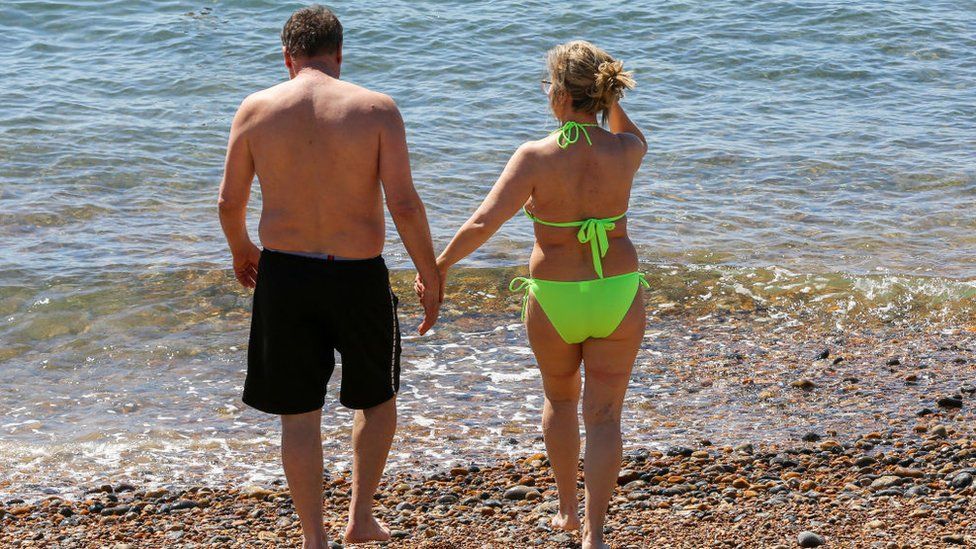 A couple walk into the sea in Brighton on the south coast of England