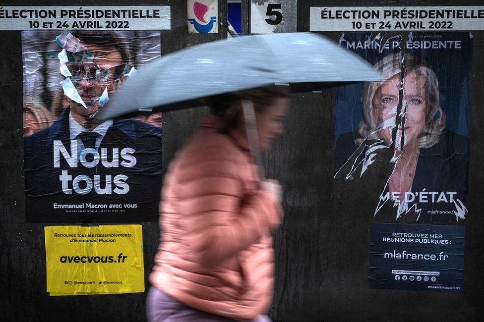 Женщина проходит мимо предвыборных плакатов в Париже, 8 апреля 2022 г.