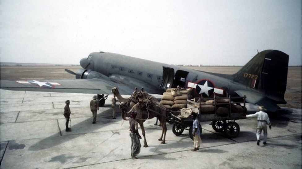 Local workers unload a Douglas Dakota Transport airplane at the U.S. Army Air Force Base in Karachi,India.