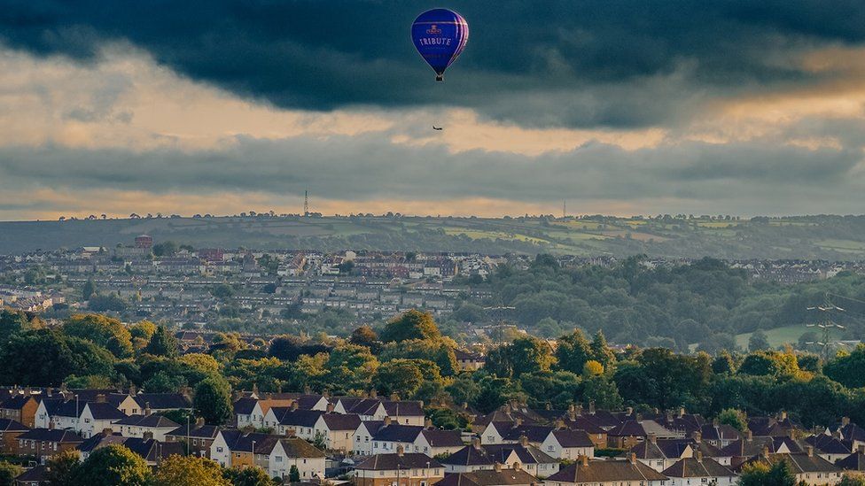 A view over Bristol from Troopers Hill Park with a hot air balloon in the distance and houses in the foreground