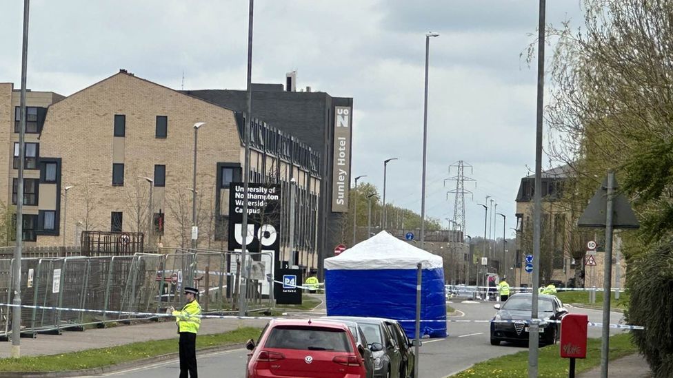 Police officers outside the University Campus. A forensic scene guard (tent) is visible