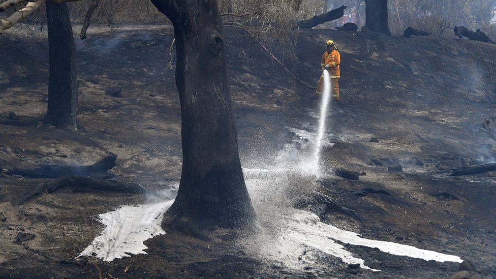 A firefighter sprays water after a fire in Melbourne, Australia, 30 December, 2019.