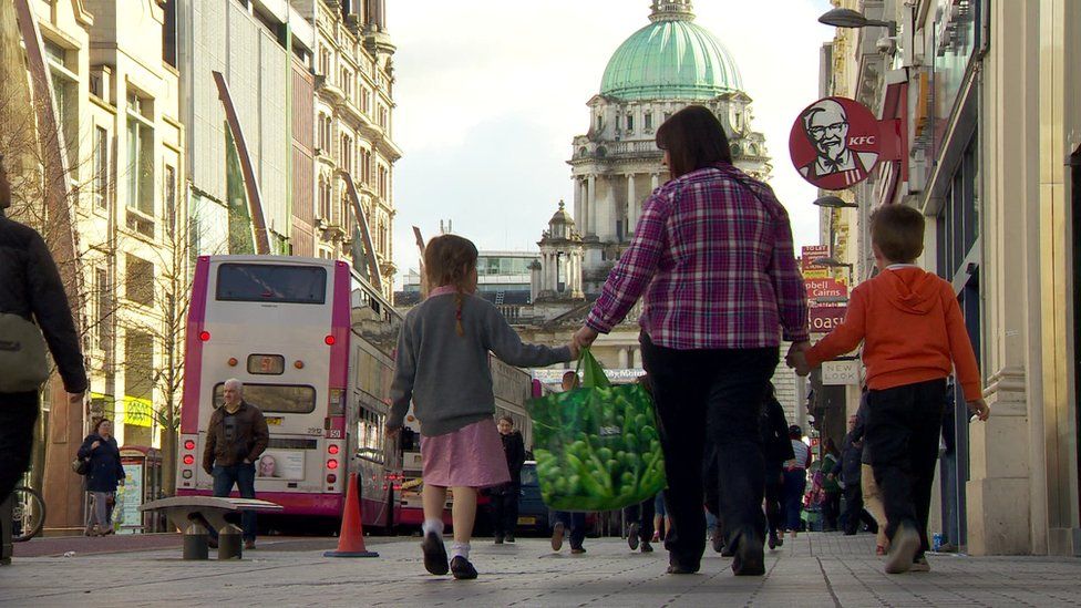 A woman walking with her son and daughter towards Belfast City Hall