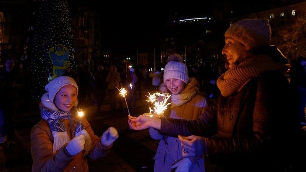 Люди собрались у елки, чтобы отпраздновать Новый год перед комендантским часом, на фоне нападения России на Украину, перед Софийским собором в Киеве, Украина