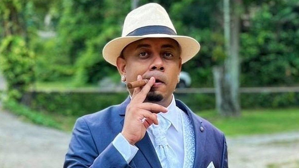 Seychelles resident Luther Denis, pictured in a suit with a Panama hat, smoking a large cigar
