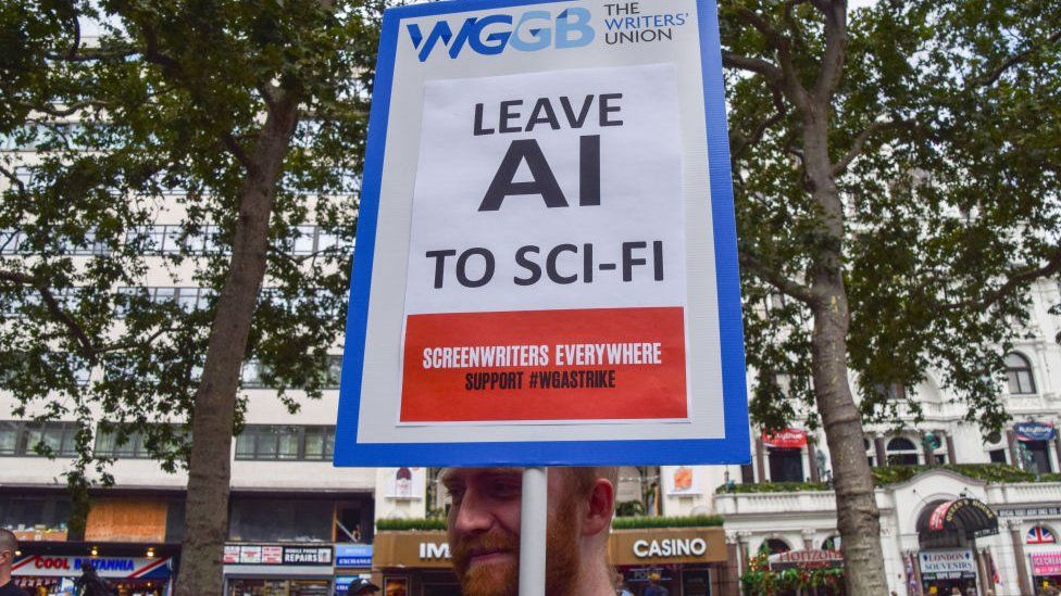 A protester holds a placard opposed to AI (Artificial Intelligence) replacing writers, at a protest organised by performing arts union Equity in solidarity striking US screenwriters.