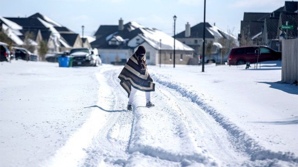 A man walks to his friend"s home in a neighbourhood without electricity as snow covers the BlackHawk neighborhood in Pflugerville, Texas, U.S. February 15, 2021.