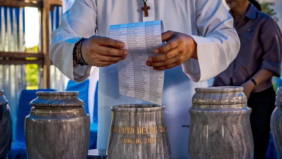 Flavie Villanueva, a Catholic priest who has been helping orphans and widows of the drug war, places a list of names of drug war victims inside an urn during the groundbreaking for the first ever memorial for victims of the drug war at the La Loma Catholic Cemetery on December 11, 2023 in Caloocan, Metro Manila