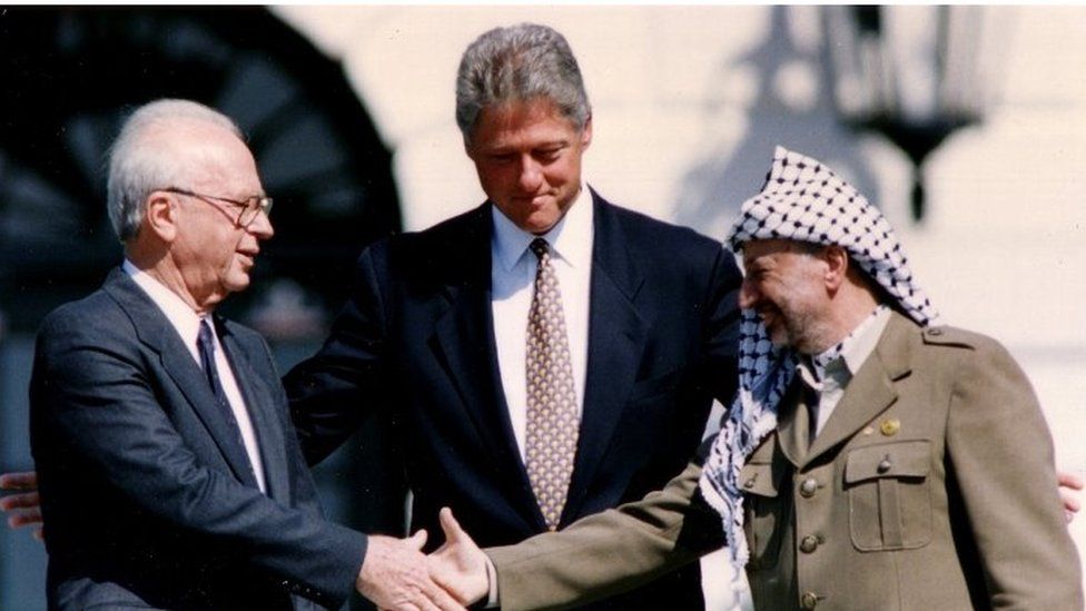 Yitzhak Rabin and Yasser Arafat shake hands as US President Bill Clinton looks on - 1993 picture