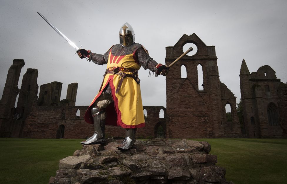 A historical actor wearing a suit of armour at Arbroath Abbey