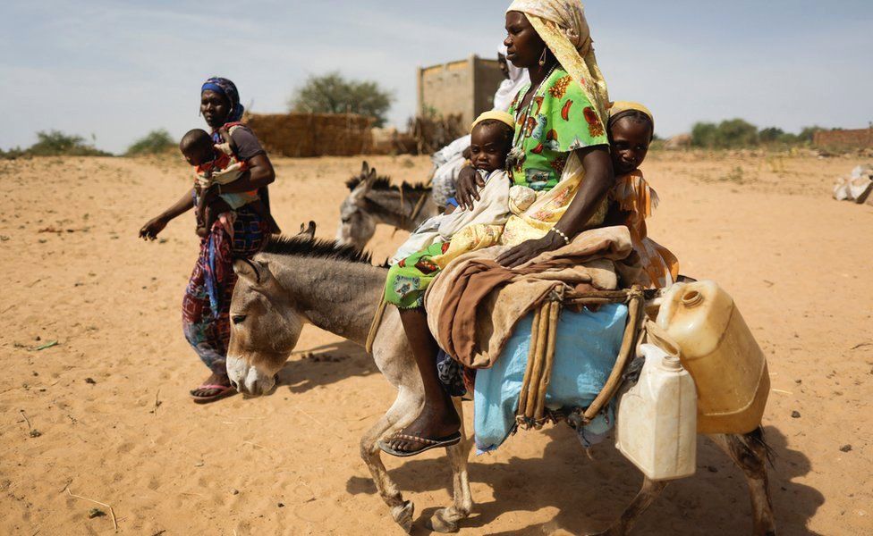 Displaced women and children successful  Darfur transportation  their belongings, assisted by donkeys