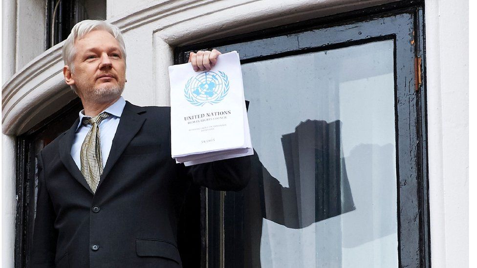 This file photo taken on 5 February 2016 shows WikiLeaks founder Julian Assange addressing the media from the balcony of the Ecuadorian embassy in central London, holding a printed report of the judgement of the UN's Working Group on Arbitrary Detention on his case.