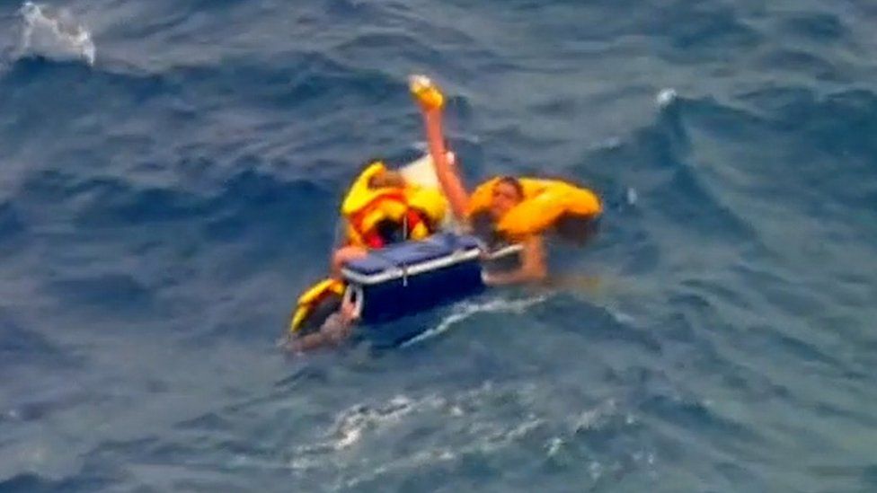 An aerial image of the three men floating at sea with the cooler