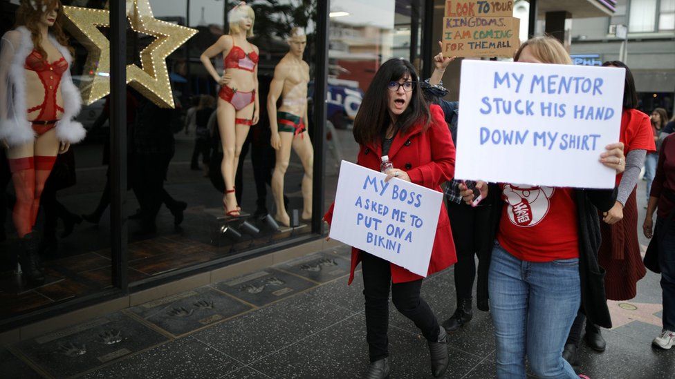 Участники марша держат плакаты на Аллее славы в Голливуде в воскресенье