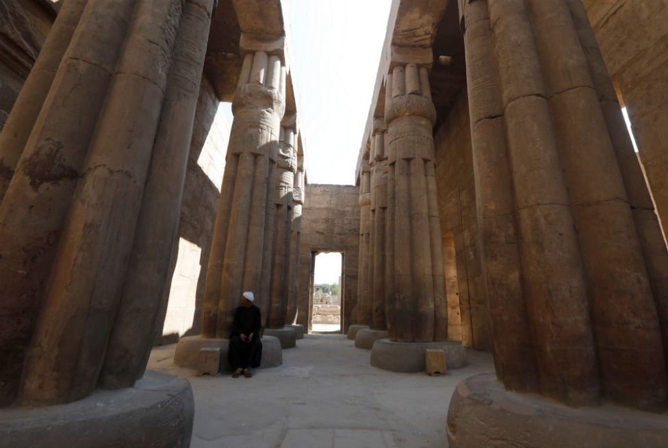 A man sits at the base of a column of Luxor Temple.