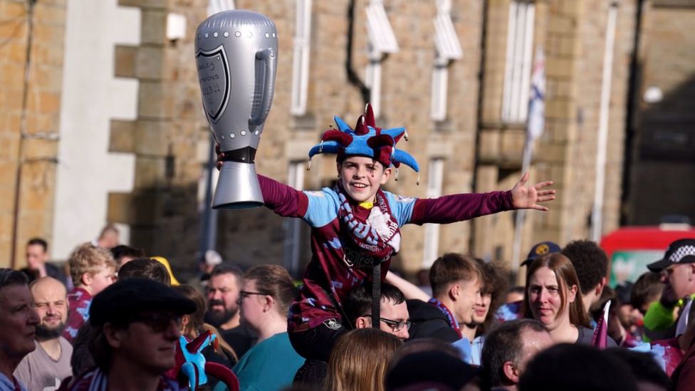 A young fan holds up an inflatable trophy