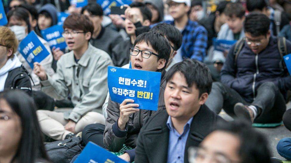 South Korean men and a few women chant slogans during a protest against #MeToo