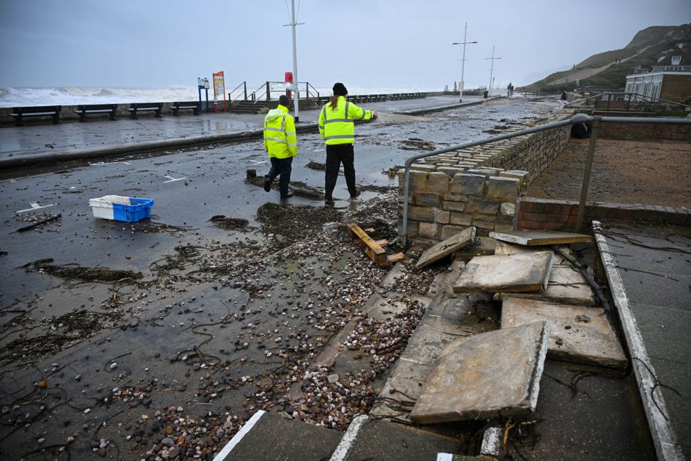 Council workers walk past damage and debris on the road, on November 02, 2023 in West Bay, Dorset.