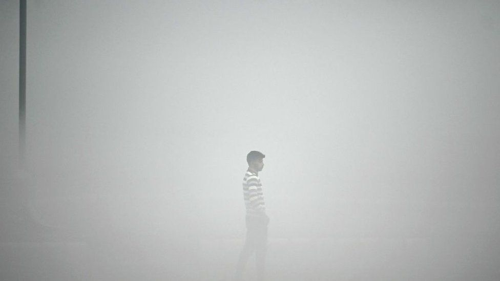 A pedestrian walks along the roadside amid heavy smoggy conditions in New Delhi on November 13, 2023.